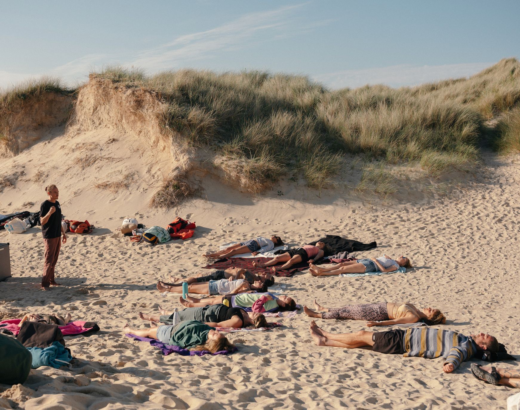 Joseph guiding an outdoor breathwork session on a beach beneath the dunes