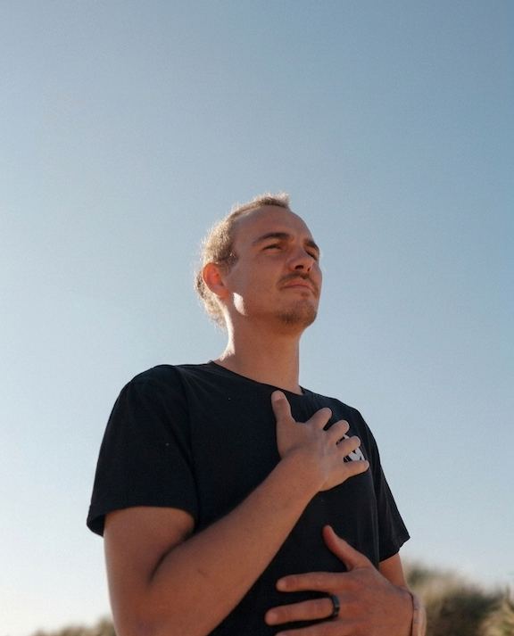 Joseph Rossi outdoors, hand on chest, looking up into the light